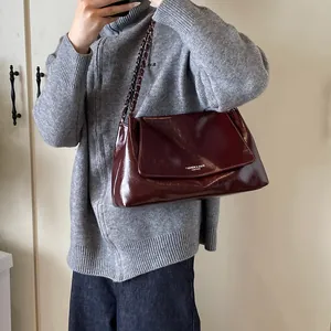Mirror shot showing a stylish burgundy tote bag with gold chain and glossy leather finish