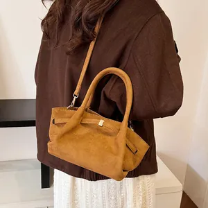 Detailed texture of brown suede tote bag featuring unique folded handles and shoulder strap