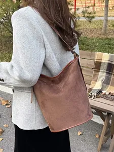 Deep brown faux suede bucket bag with leather trim on a woman wearing an autumn coat