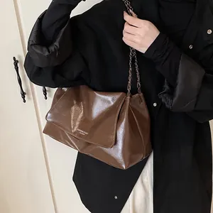 Detailed shot of dark brown tote bag with metal chain strap and leather texture