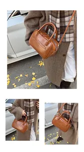 Detailed view of brown retro glossy PU leather handbag with dual handles and metal zipper