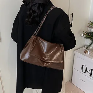 Detail shot of a dark brown glossy leather tote bag with stylish chain strap for women