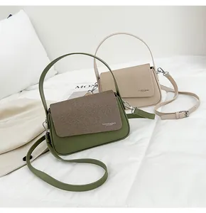 Détail du sac à main bicolore avec texture cuir et rabat en tissu sergé avec logo élégant