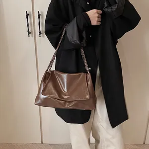 Detail of coffee brown faux leather shoulder bag with vintage chain and fashion text