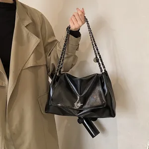 Detail of a black glossy chain shoulder bag with FASHION & BAGS LEATHER print logo