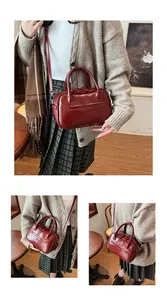 Detail view of burgundy leather Boston bag with dual handles and adjustable shoulder strap