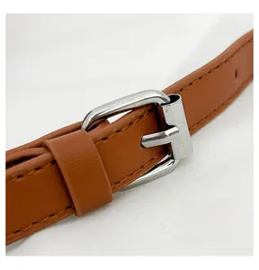Détail de la bandoulière réglable en cuir marron avec boucle en métal argenté et couture
