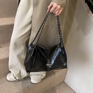 Detail of glossy black tote bag with chain strap and white printed lettering on the side