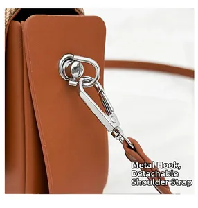 Détail du crochet métallique argenté et de la bandoulière amovible en cuir caramel