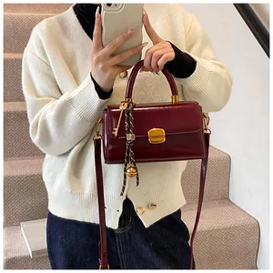 Detail der Vintage-Lederhandtasche mit Goldverschluss und kreativem Anhänger