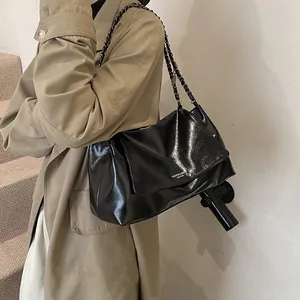 Detail of black glossy leather tote bag with chain strap and fashion logo lettering