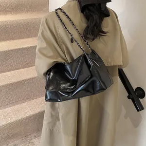 Detail of black leather chain bag with fashion text engraving on beige trench coat
