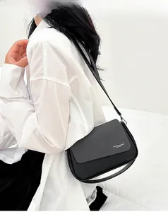 Détail du sac bandoulière noir montrant la texture cuir diagonale et les finitions du rabat