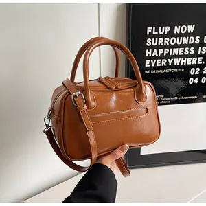 Detail of caramel brown PU leather bag with glossy finish and cylindrical top handles