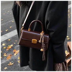 Detail einer dunkelbraunen Vintage-Handtasche aus Leder mit Goldschloss und Herbstlaub