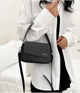 Détail d'un sac bandoulière noir minimaliste avec rabat asymétrique et texte blanc