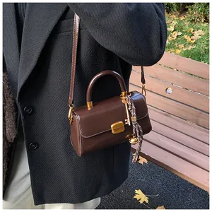 Detailansicht der dunkelbraunen Ledertasche mit goldener Schnalle und Anhängern