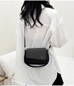 Détail d'un sac bandoulière noir avec rabat texturé et imprimé mode porté par mannequin