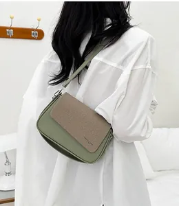 Vue détaillée d'un sac bandoulière bicolore vert et marron porté par un mannequin