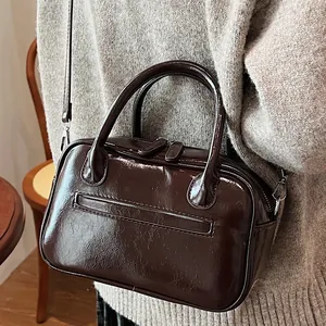 Deep brown glossy leather handbag with double handles and crossbody strap for women