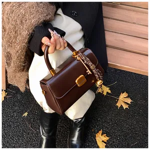 Detail der dunkelbraunen Vintage-Handtasche mit Goldschloss und Schlüsselanhänger-Dekor