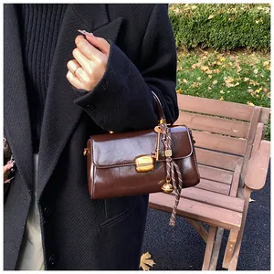 Detail der dunkelbraunen Vintage-Ölwachsledertasche mit goldener Schnalle und Glockenanhänger