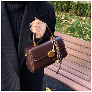 Nahaufnahme der dunkelbraunen Vintage-Handtasche mit Goldschloss und dekorativen Anhängern