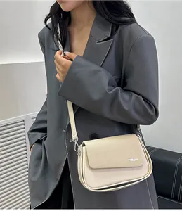 Détail du sac bandoulière crème avec texture textile sur le rabat et finitions argentées
