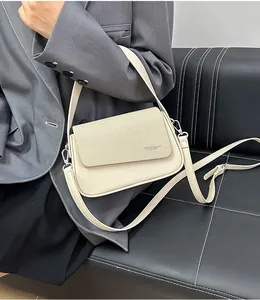 Détail du sac bandoulière crème avec rabat texturé et attaches métalliques dorées chic