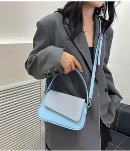 Détail du sac à bandoulière contrasté en cuir bleu clair avec rabat en tissu texturé