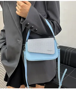 Détail du sac bandoulière carré bleu clair avec rabat texturé et inscription