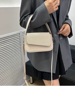 Détail d'un sac à main beige présentant une texture sergé et des ferrures argentées