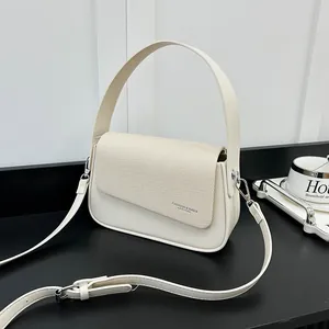 Détail d'un sac à main blanc crème avec rabat tissé et deux bandoulières réglables