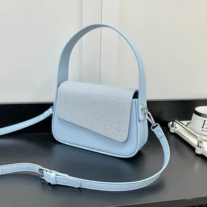 Détail du sac bandoulière bleu clair avec empiècement en tissu et boucle en métal argenté