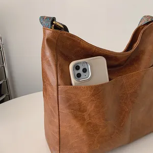 Nahaufnahme der braunen PU-Hobo-Tasche mit Vordertasche und geometrischem Gurt