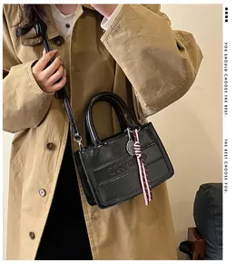 Detail of black faux leather tote with MH.3DU embossed text and tennis racket charm