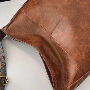 Detailansicht der dunkelbraunen PU-Ledertasche mit gewebtem Riemen und goldener Schnalle