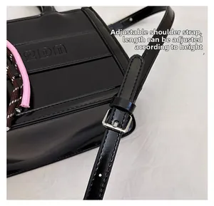 Detail of adjustable shoulder strap and glossy black leather surface on tote bag
