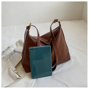 Detail view of large brown leather tote bag with gold ring buckle and tablet for scale
