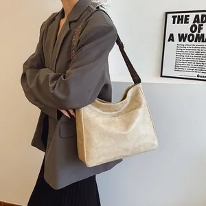 Detail der beigen Kunstledertasche mit Jacquard-Gurt und vorderer Einstecktasche