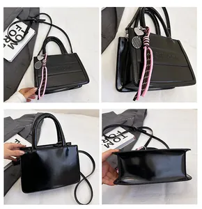 Detail of glossy black tote bag with embossed letters and heart-shaped tennis racket charms