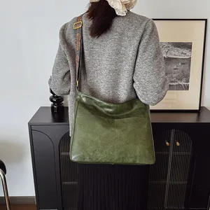 Modell mit dunkelgrüner Kunstleder-Umhängetasche mit gewebtem Riemen mit Muster
