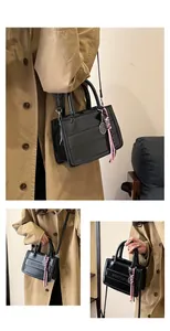 Detail of black glossy leather tote bag with tennis racket charm and rope tassel decoration