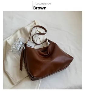 Detailed view of brown leather tote bag with adjustable strap and vintage gold buckle