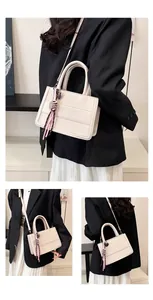 Detail of beige faux leather tote with embossed lettering and silk ribbon charm