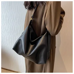 Detailed view of black matte leather tote bag with golden metal buckle and shoulder strap