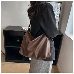 Detailed side view of a large brown leather hobo bag with gold buckle for commuting