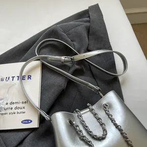 Close-up of silver metallic bucket bag with chain strap on dark grey blazer