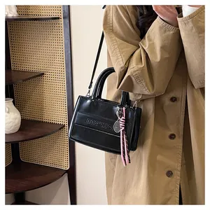 Detail of black PU leather tote with silver tennis racket charm and woven pendant