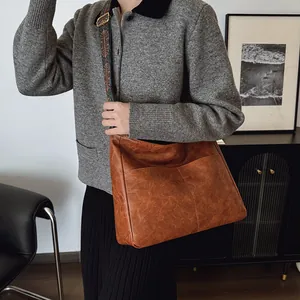 Detail einer braunen Ledertasche mit farbenfroh besticktem breitem Schultergurt